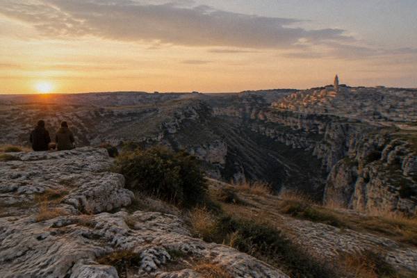 Sun low over the Murgia plateau with the Sassi in silhouette across the canyon