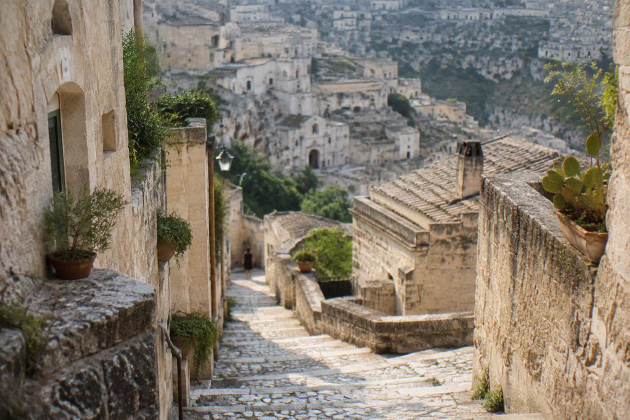 A stone stairway descending between pale cave houses in the Sassi of Matera