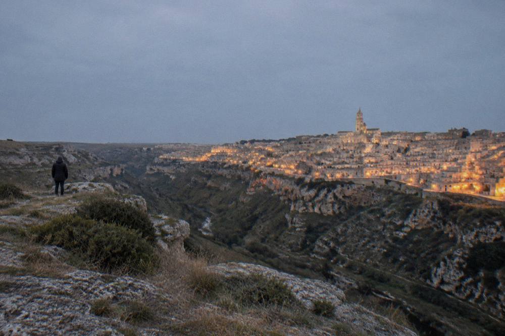 The illuminated cave houses of the Sassi seen at night from across the Gravina canyon
