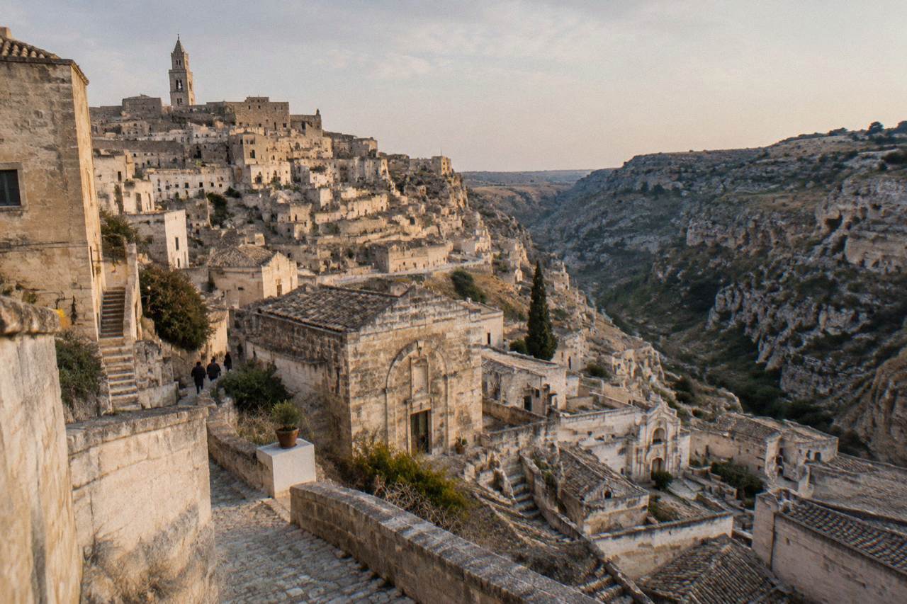 Pale stone cave dwellings of the Sassi rising above a deep canyon at dusk