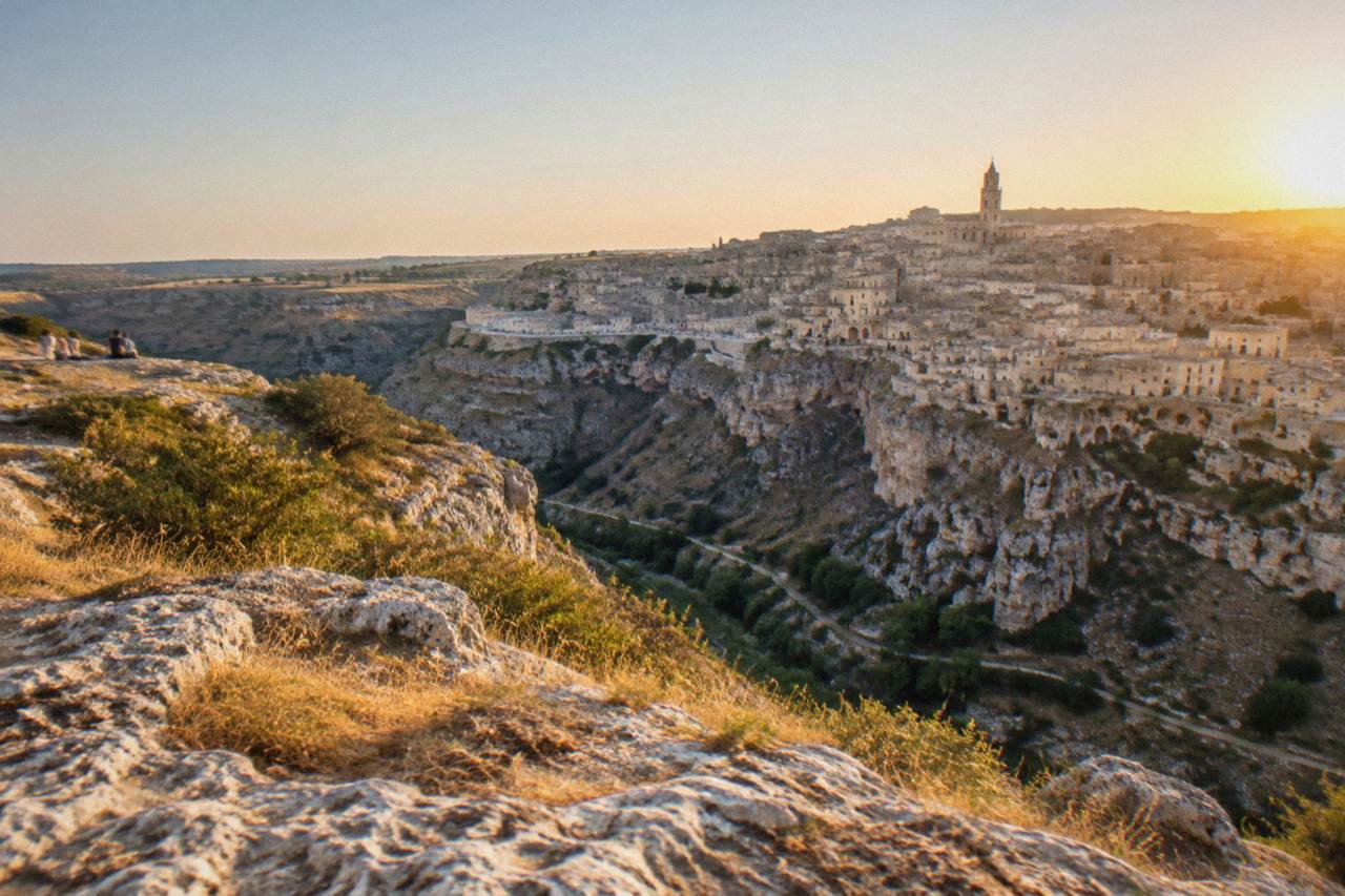 Panoramic view of the Sassi cave dwellings of Matera rising above the Gravina canyon at golden hour