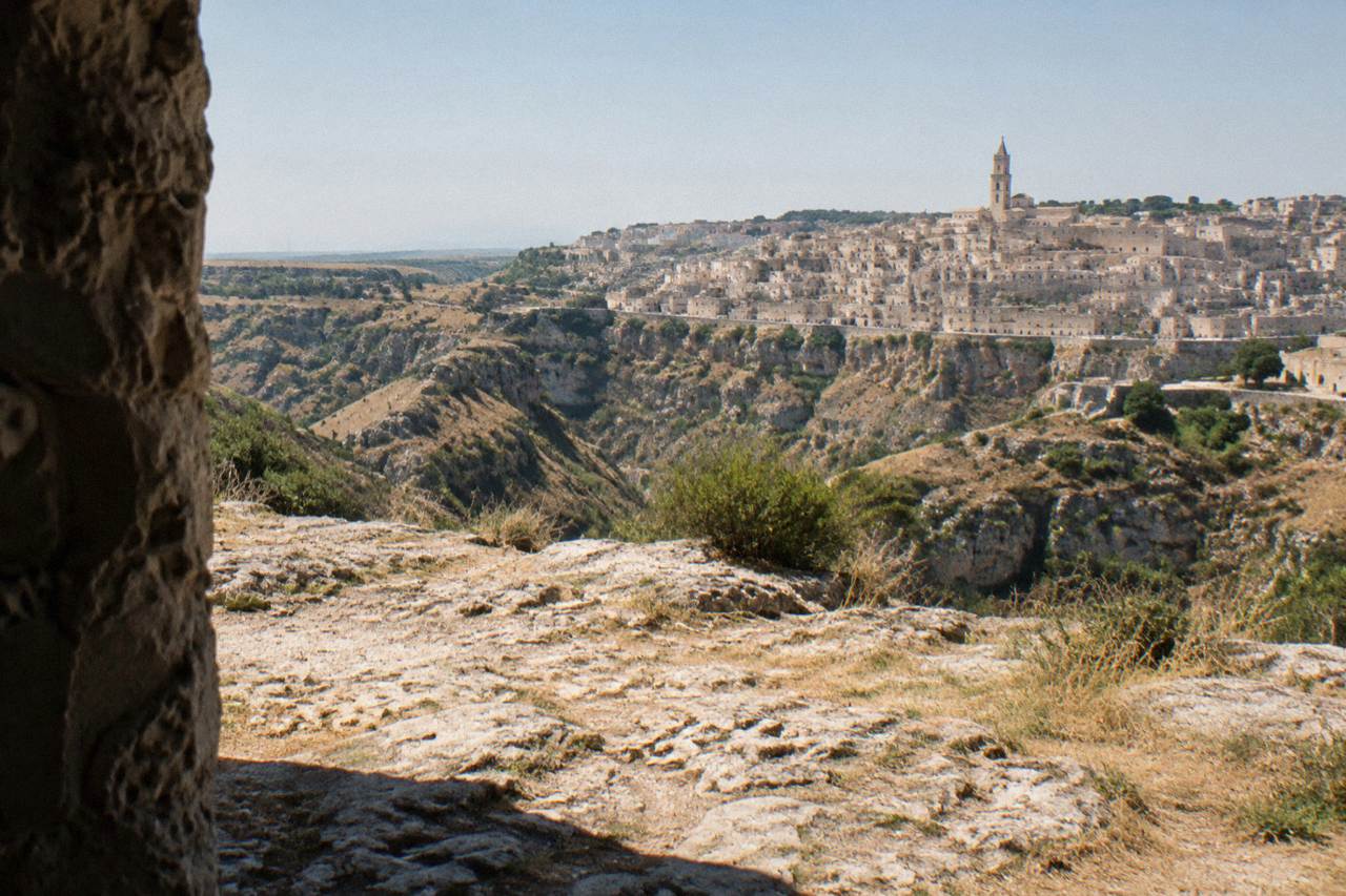 Pale stone cave houses of the Sassi di Matera stacked above the Gravina canyon at golden hour