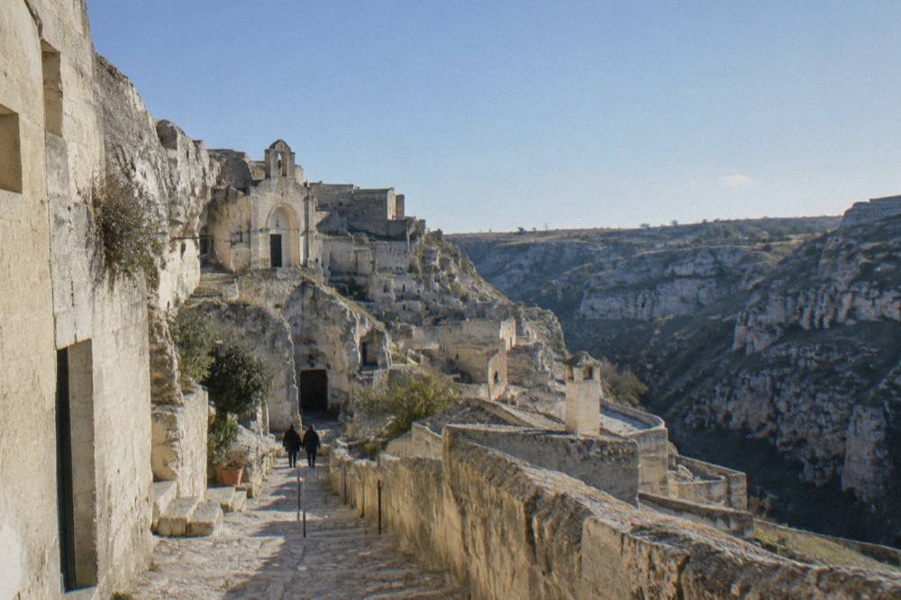 A narrow stepped lane between stone facades and cave doorways in the Sasso Caveoso quarter