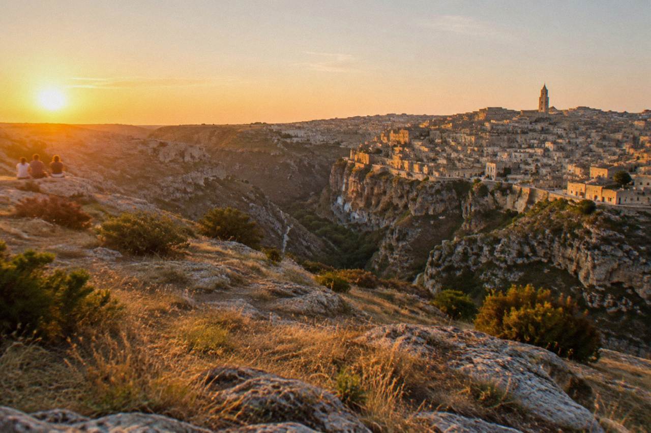The Sassi district of Matera glowing in warm evening light above the Gravina canyon
