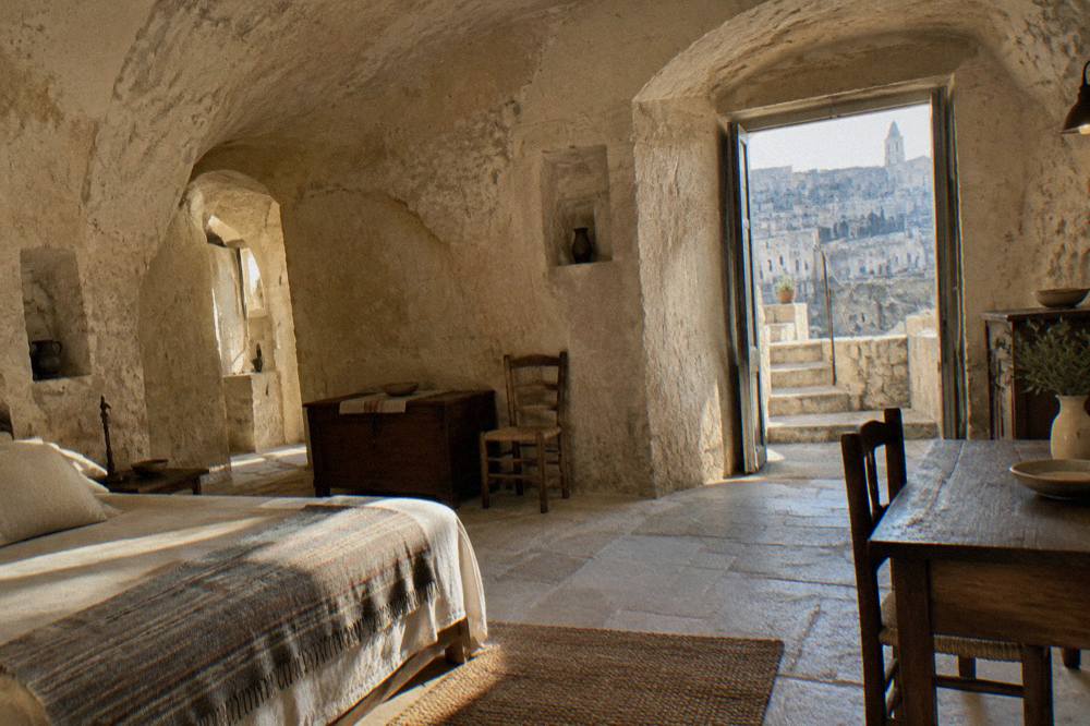 A restored cave dwelling interior in Matera with stone walls, arched ceilings and simple period furnishings