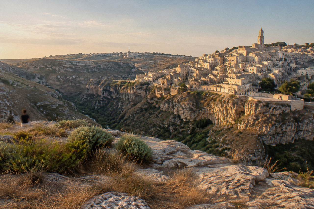 Pale stone cave dwellings of the Sassi district in Matera rising above the Gravina canyon at golden hour