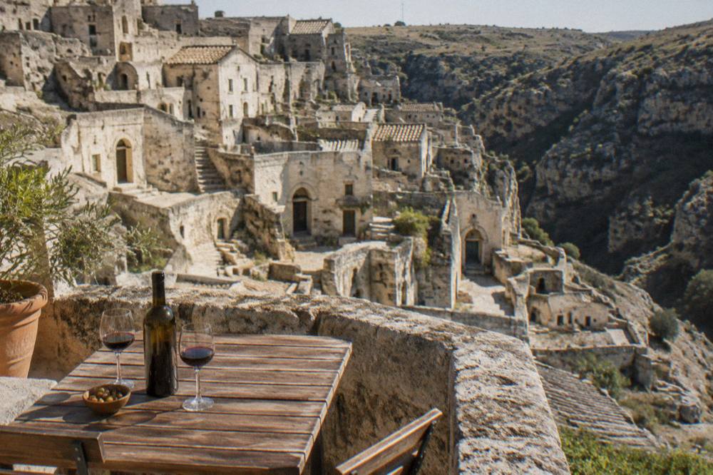 A stone terrace table set at dusk overlooking cave dwellings across a deep canyon