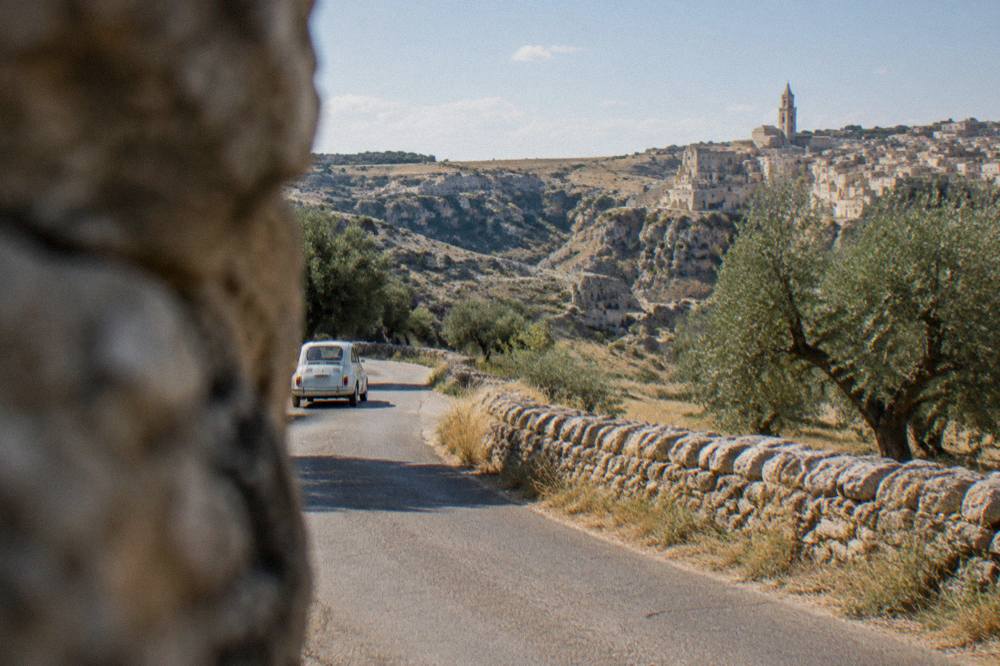An open country road on the Murgia plateau near Matera with dry stone walls and olive trees