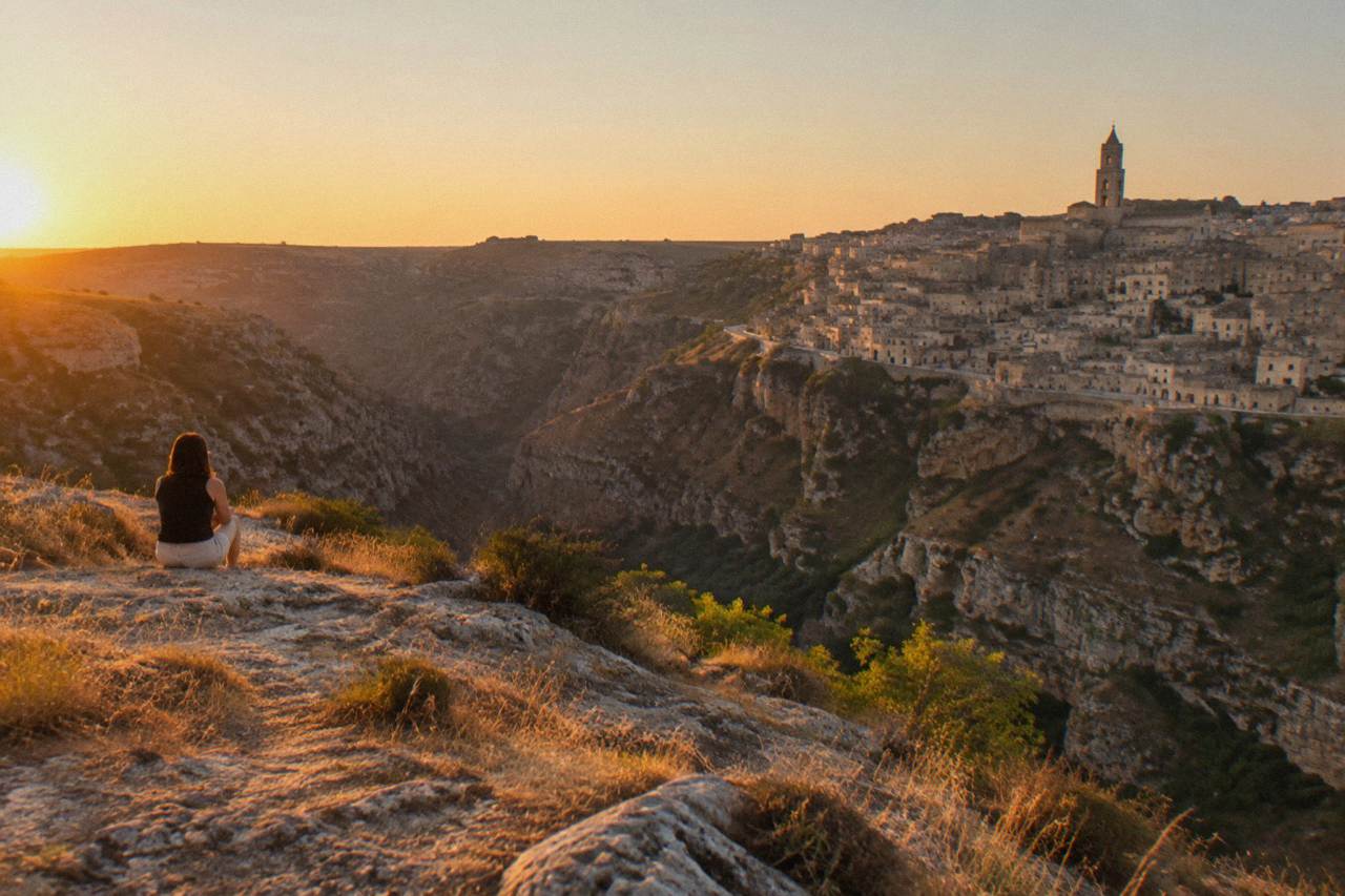 Pale limestone cave dwellings stacked along the edge of the Gravina canyon in the Sassi of Matera