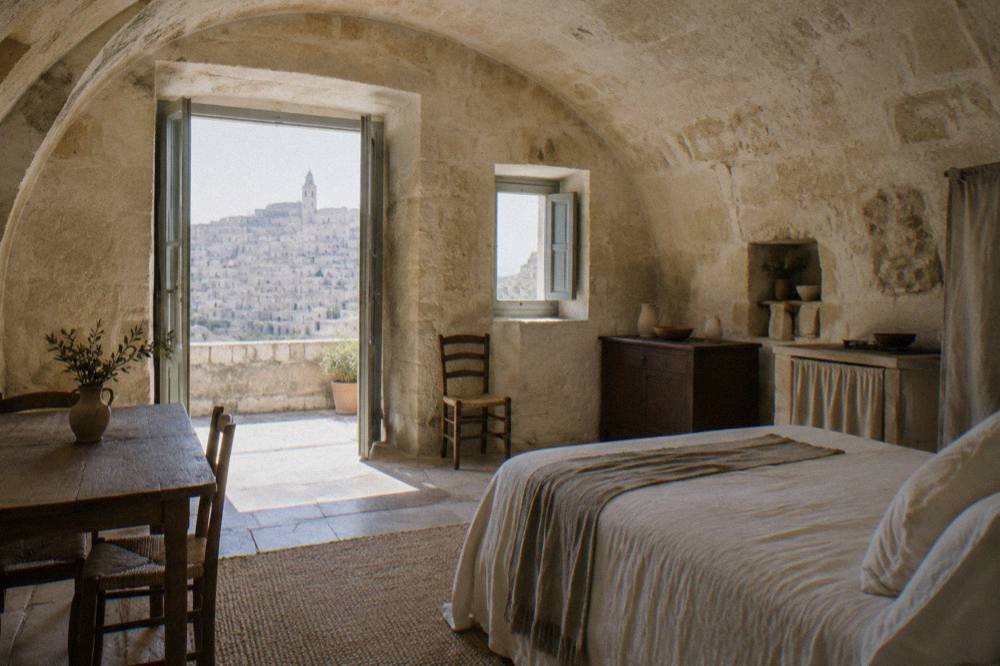 A restored cave house interior in Matera with stone walls, an arched ceiling and simple rustic furnishings