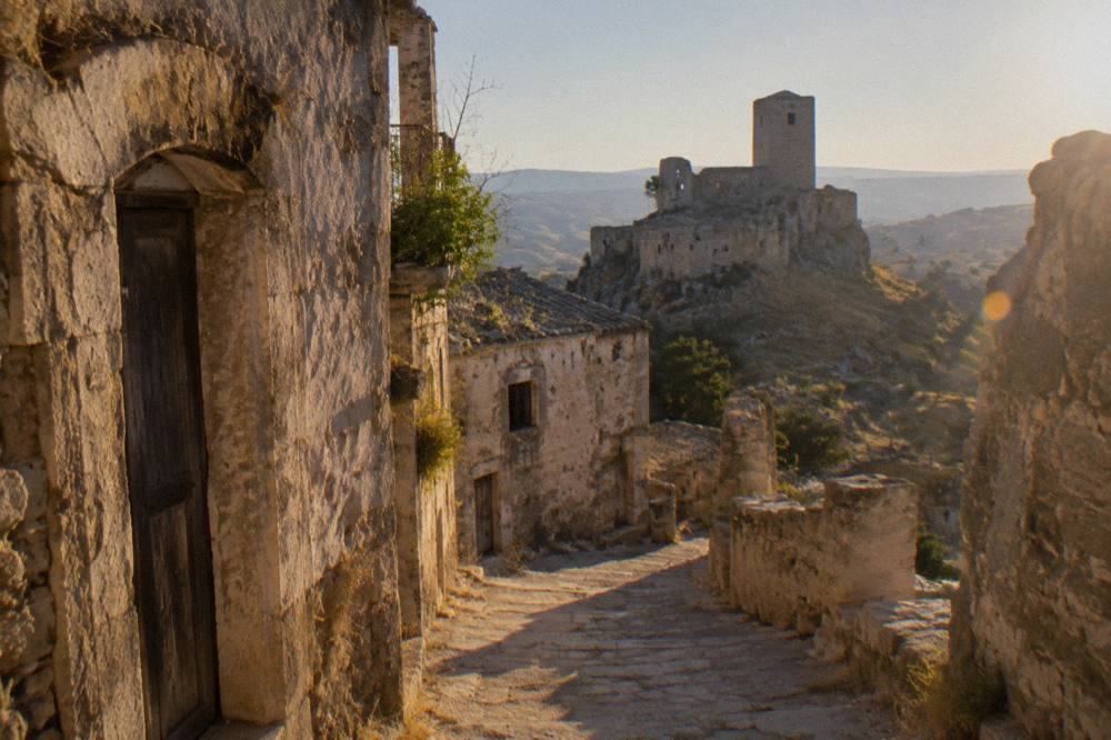 Empty stone street in an abandoned hill town with weathered facades and a view over bare hills