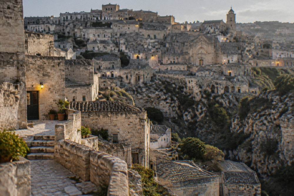 Evening lights on the stone facades above the canyon in Matera