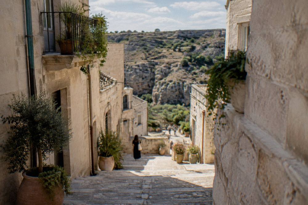 Stone steps descending between pale cave buildings toward a canyon landscape