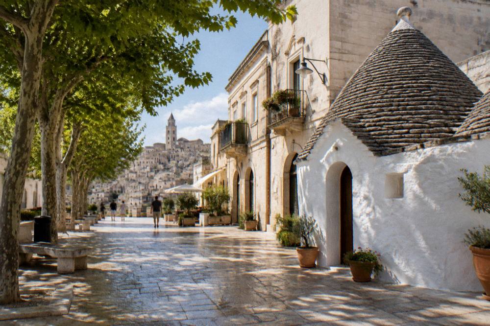 A white trullo building with a conical stone roof in a small southern Italian town
