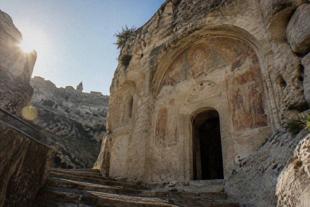 Rock-cut church facade with a weathered fresco carved into pale tufa in Sasso Caveoso