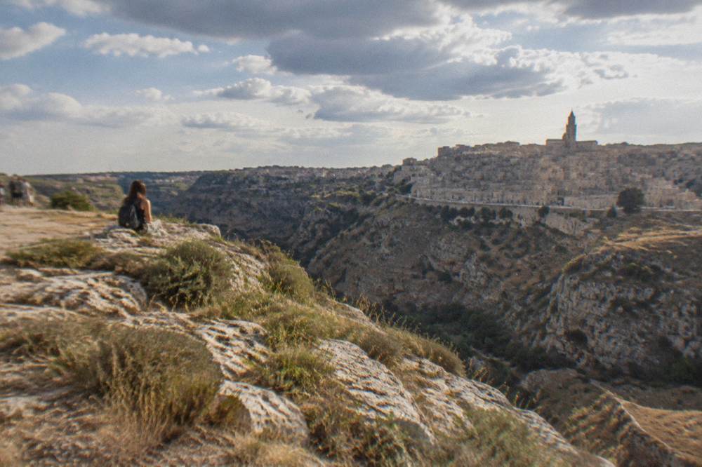 View from the Murgia side across the Gravina gorge toward the stacked Sassi rooftops