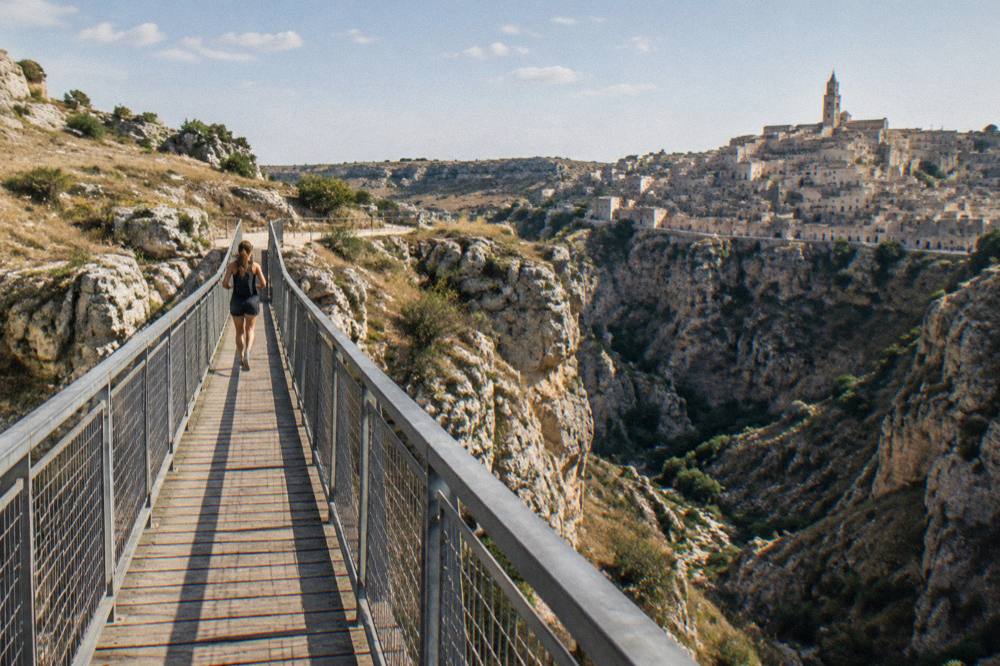 A narrow footbridge spanning a deep rocky gorge between limestone cliffs