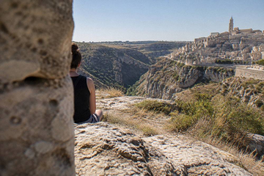 A wide evening panorama of a canyon with a stone city on one rim and open plateau on the other