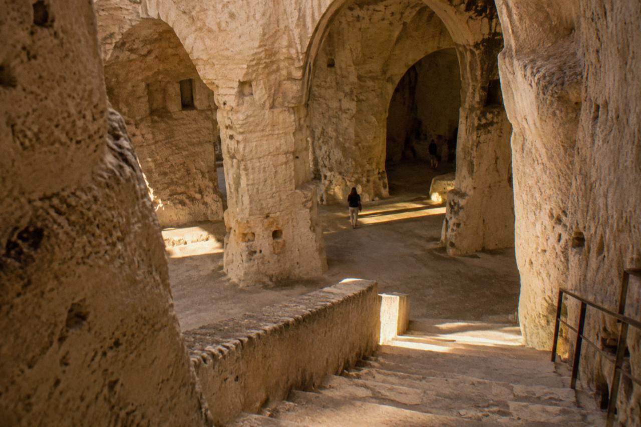 A stone stairway leading down into a vaulted underground space carved from pale tufa rock