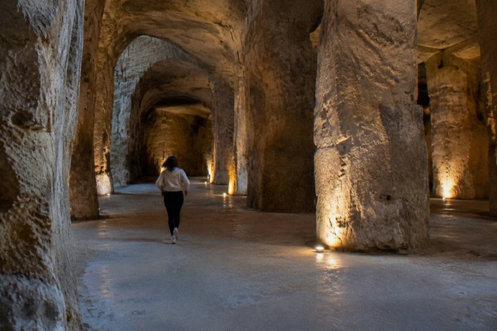 A deep stone-walled cistern chamber with a vaulted ceiling lit by warm spotlights