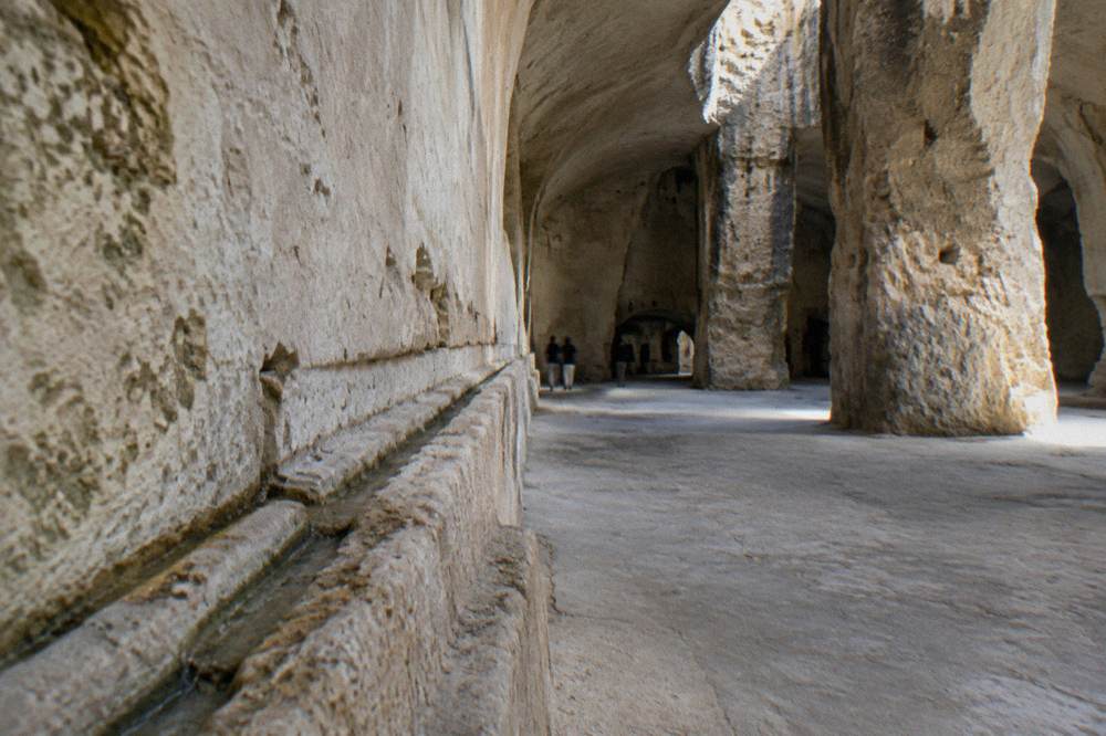 Carved water channel grooves running along a pale stone wall inside an underground chamber