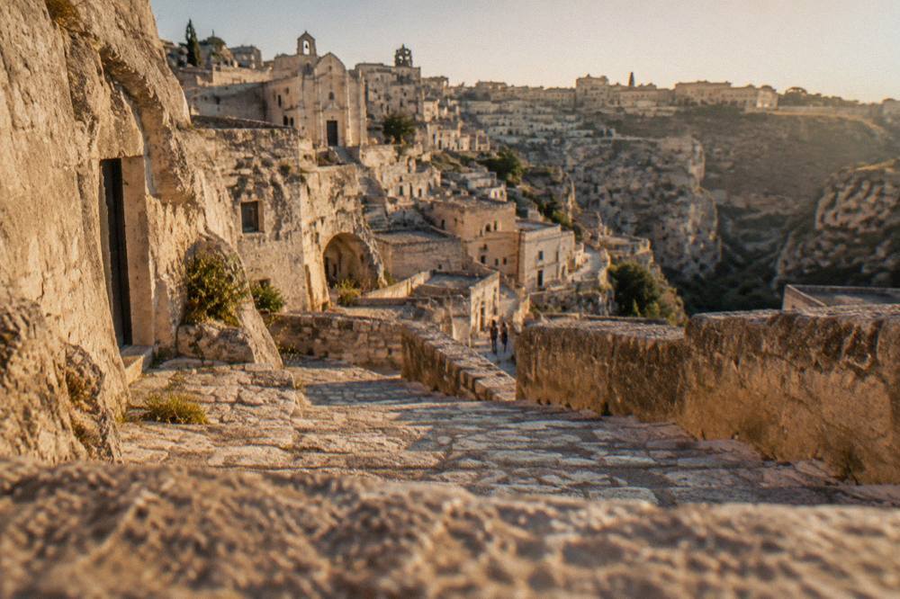 Stone staircases and cave facades in the Sassi at golden hour with long shadows