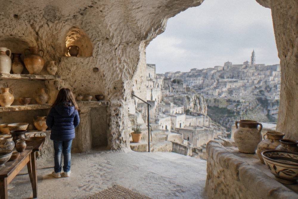 A child looking at pottery vessels displayed inside a cave house in Matera