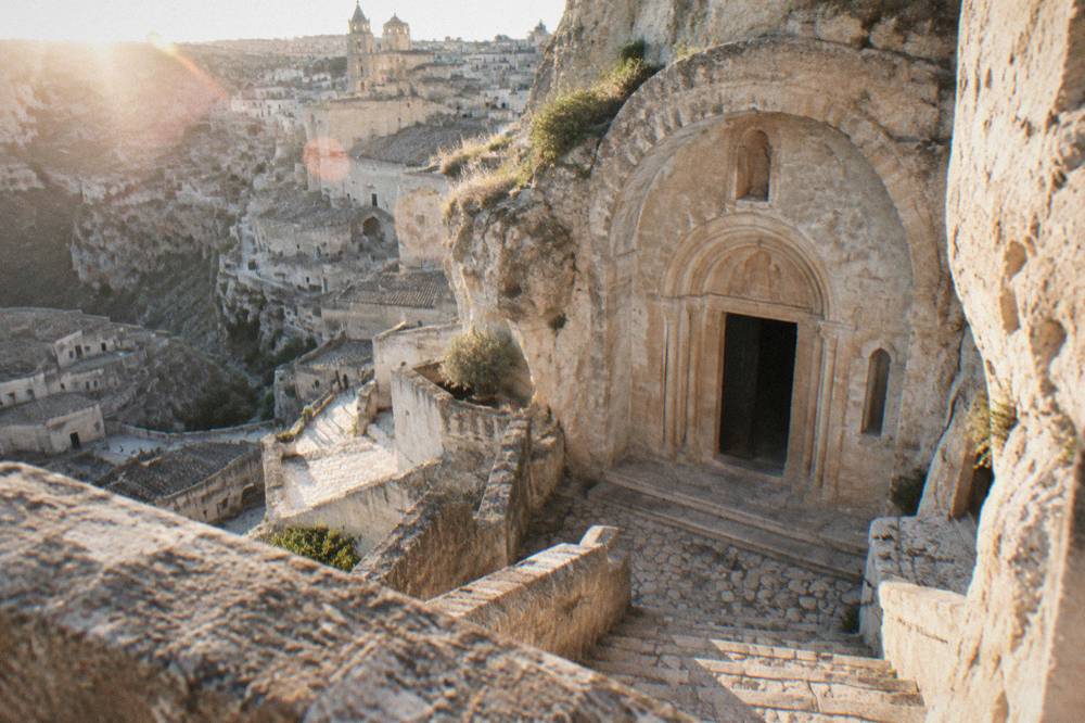 A rock-cut church doorway carved into pale limestone in the Sassi of Matera