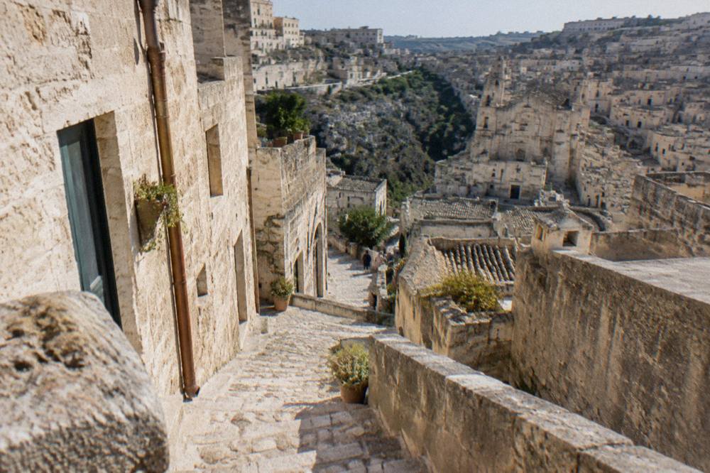 A narrow stepped alley between pale stone cave dwellings in Matera