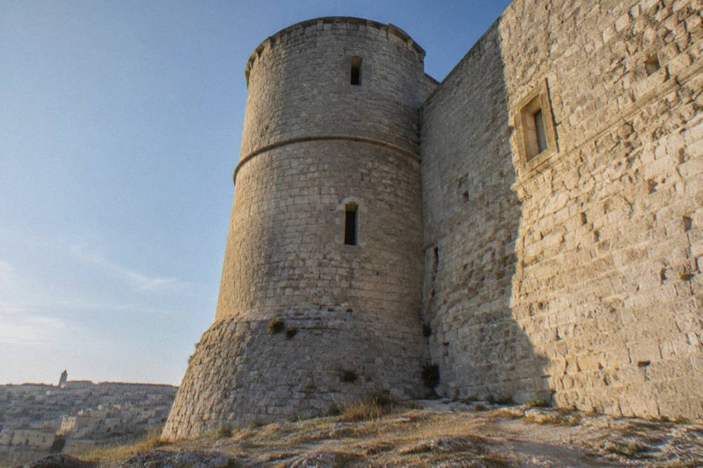 Close view of the rough stone wall and base of a round tower at Castello Tramontano