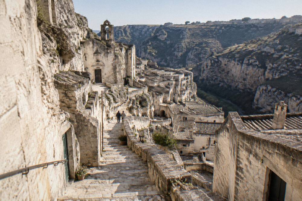 Steep stone staircases and pale cave house facades descending through the Sasso Caveoso in Matera