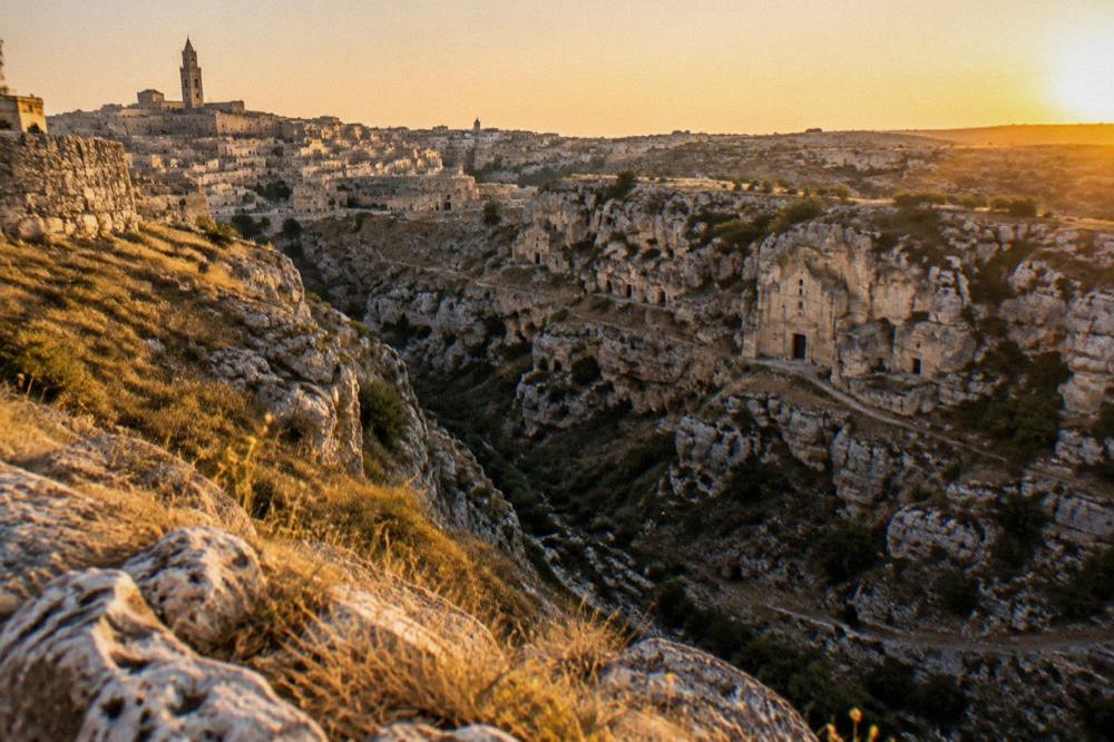 Rock-cut church facades dotted along the cliffs of the Murgia plateau seen from Matera