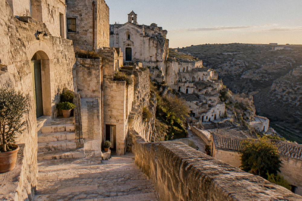 Restored cave house facades with stone stairways in the Sasso Caveoso of Matera at golden hour
