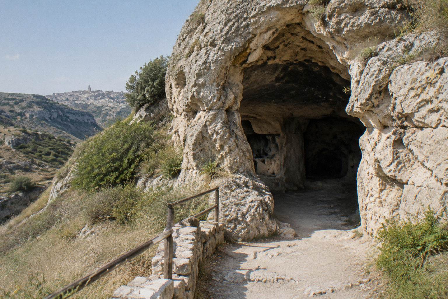 Cave mouth in a limestone rock face on a rural hillside in the Murgia countryside