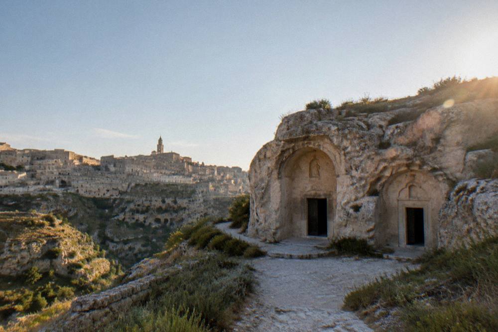 A canyon wall honeycombed with cave openings beneath stone houses