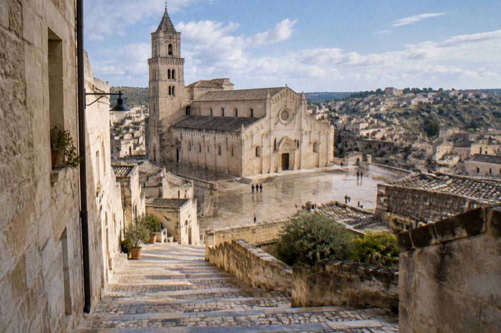 A narrow stepped lane of pale stone leading up toward Matera Cathedral