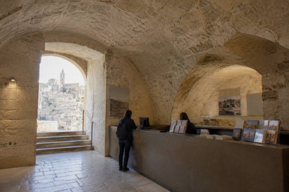 A museum ticket desk in a stone vaulted room in Matera