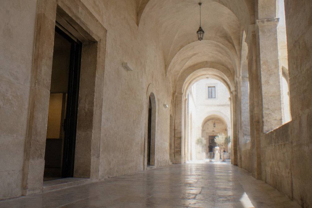 A long stone corridor inside a palazzo museum with arched doorways