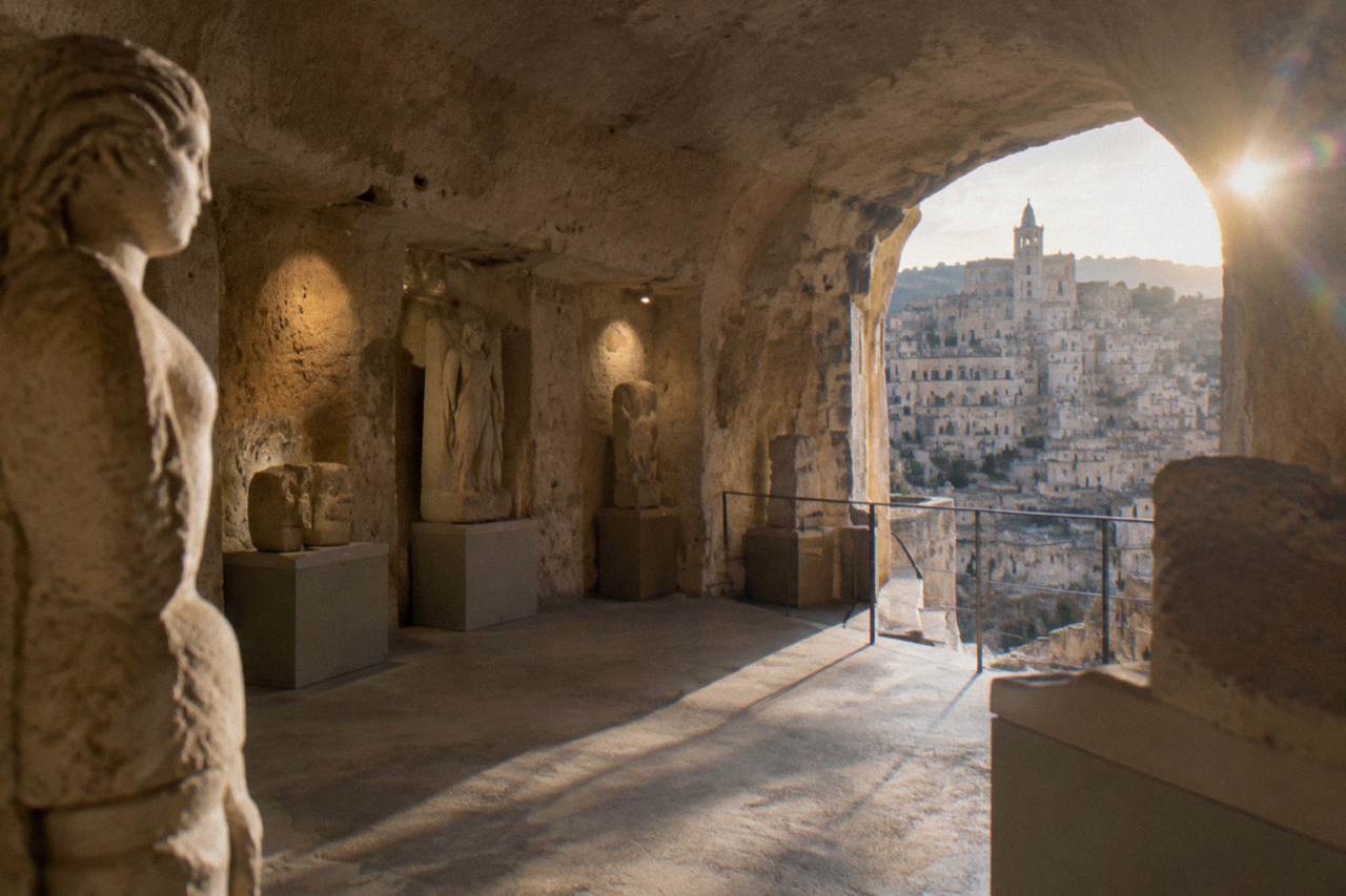 Stone cave interior of a museum in Matera with sculptures displayed along the walls