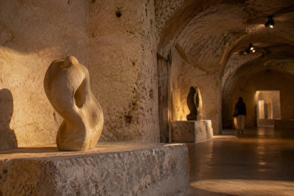 Sculpture on a stone ledge lit by warm light in a cave museum room