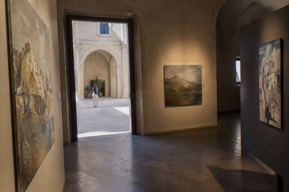 Painted wooden panels and canvases displayed in a dim gallery inside Palazzo Lanfranchi