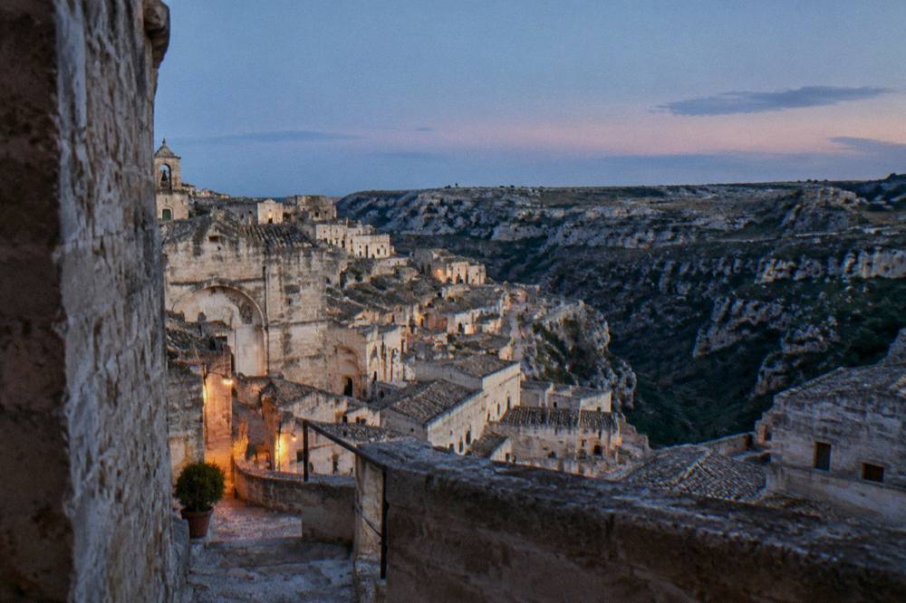 The Sasso Caveoso rooftops seen from the palace rim at dusk with the Murgia plateau opposite