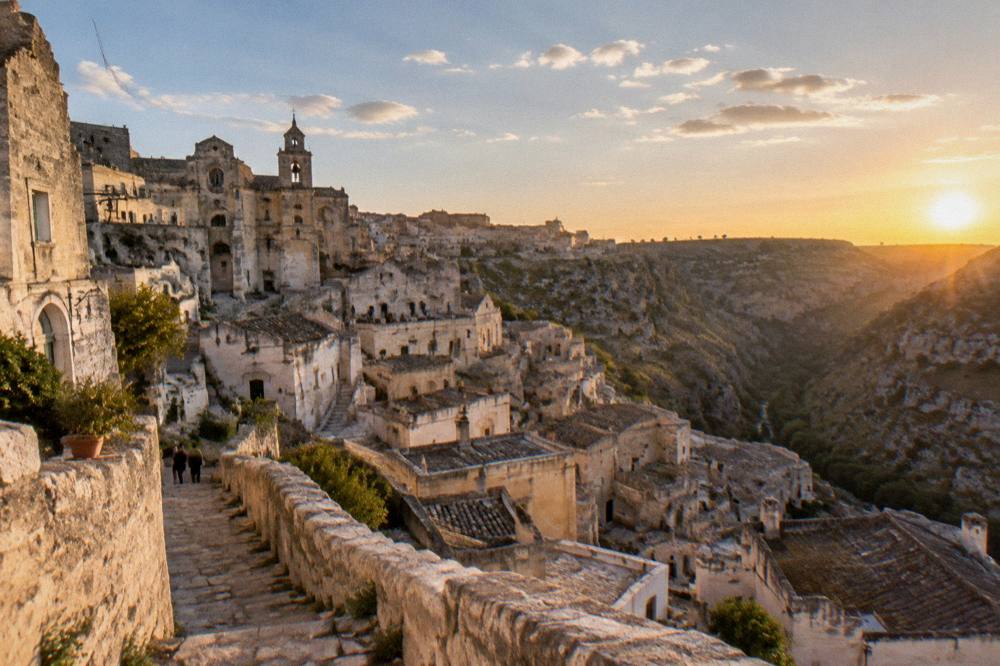 Panorama of pale stone Sassi rooftops descending toward a deep canyon at golden hour