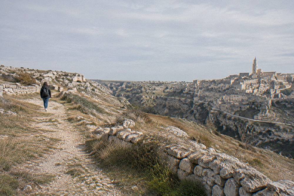 A grassy plateau path with low stone walls under a wide sky on the Murgia