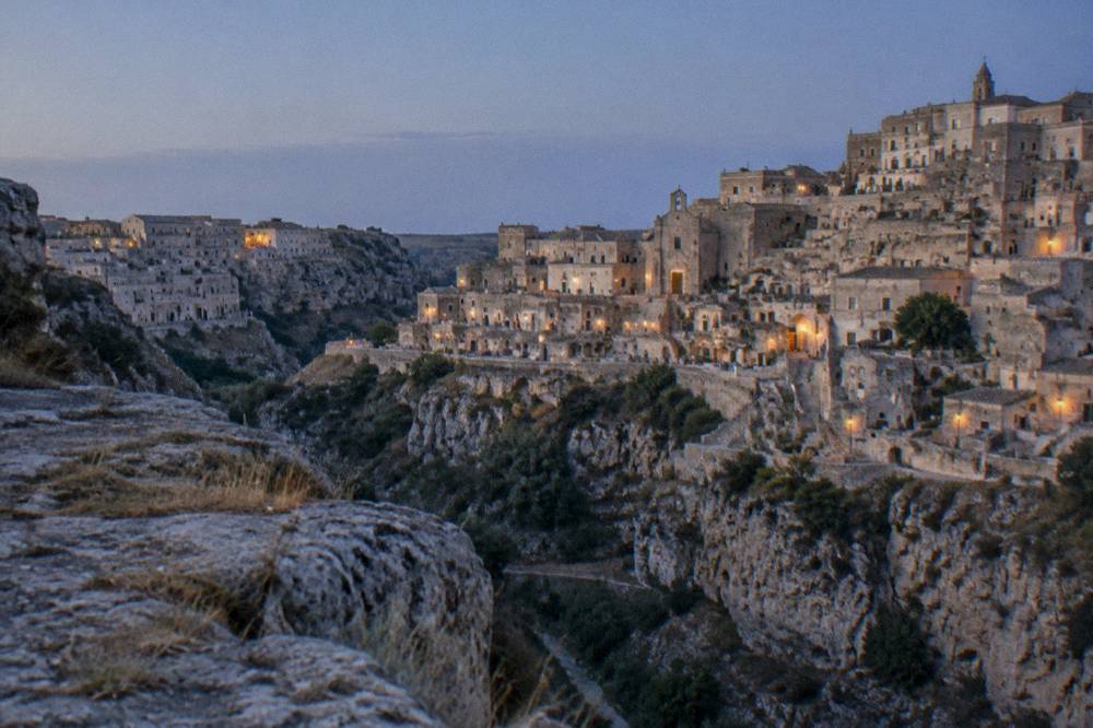 The stacked cave dwellings of the Sassi seen from a rocky terrace across the canyon