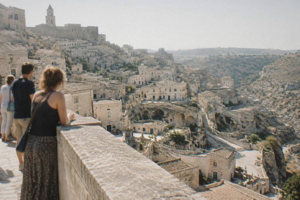 Visitors looking out from a stone balustrade over the cave dwellings of Sasso Barisano in Matera