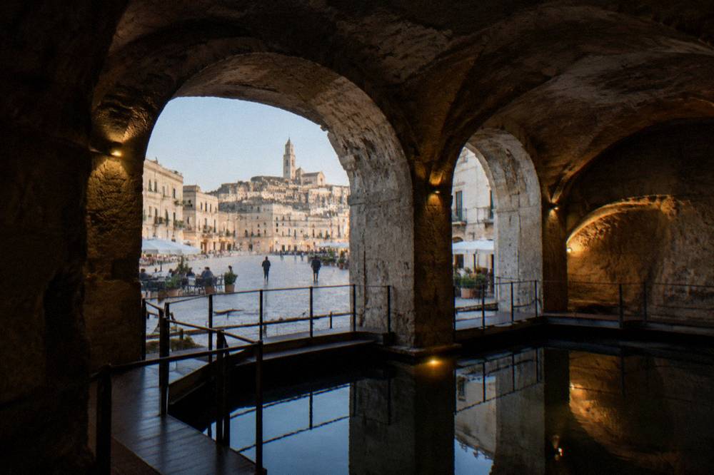 A dark vaulted underground cistern carved from stone with walkways and dim lighting