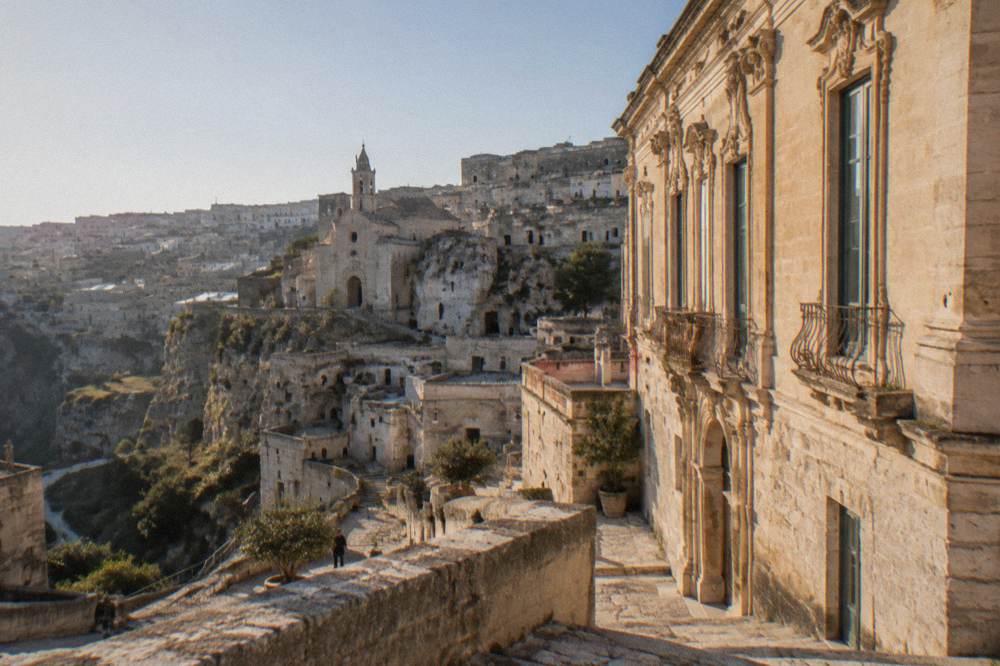 A baroque stone palace facade with tall windows in Matera under a clear sky