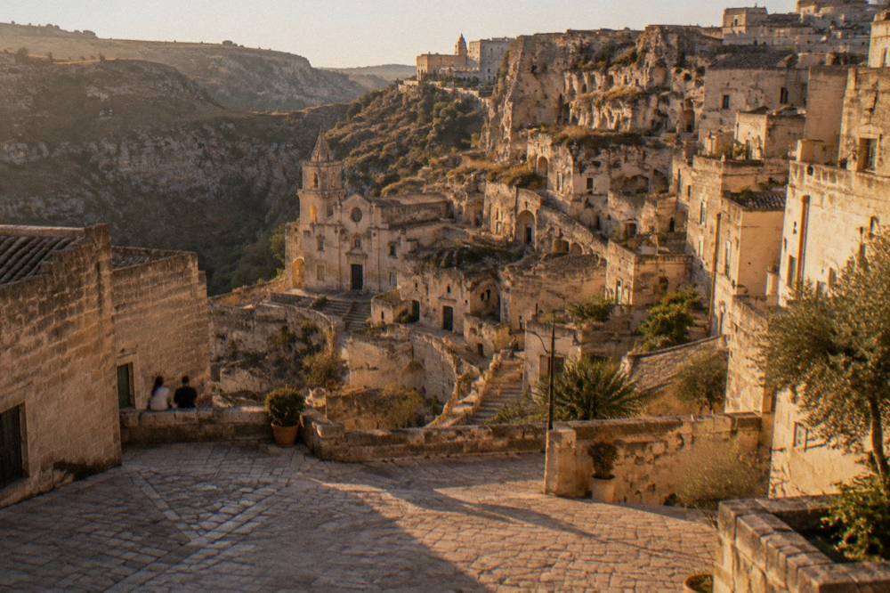 Evening light on the terraced cave facades of the Sassi seen from a stone square in Matera