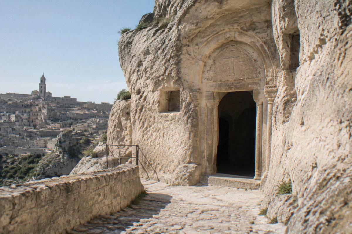 Rock-hewn church entrance cut into a pale cliff face above a stone path